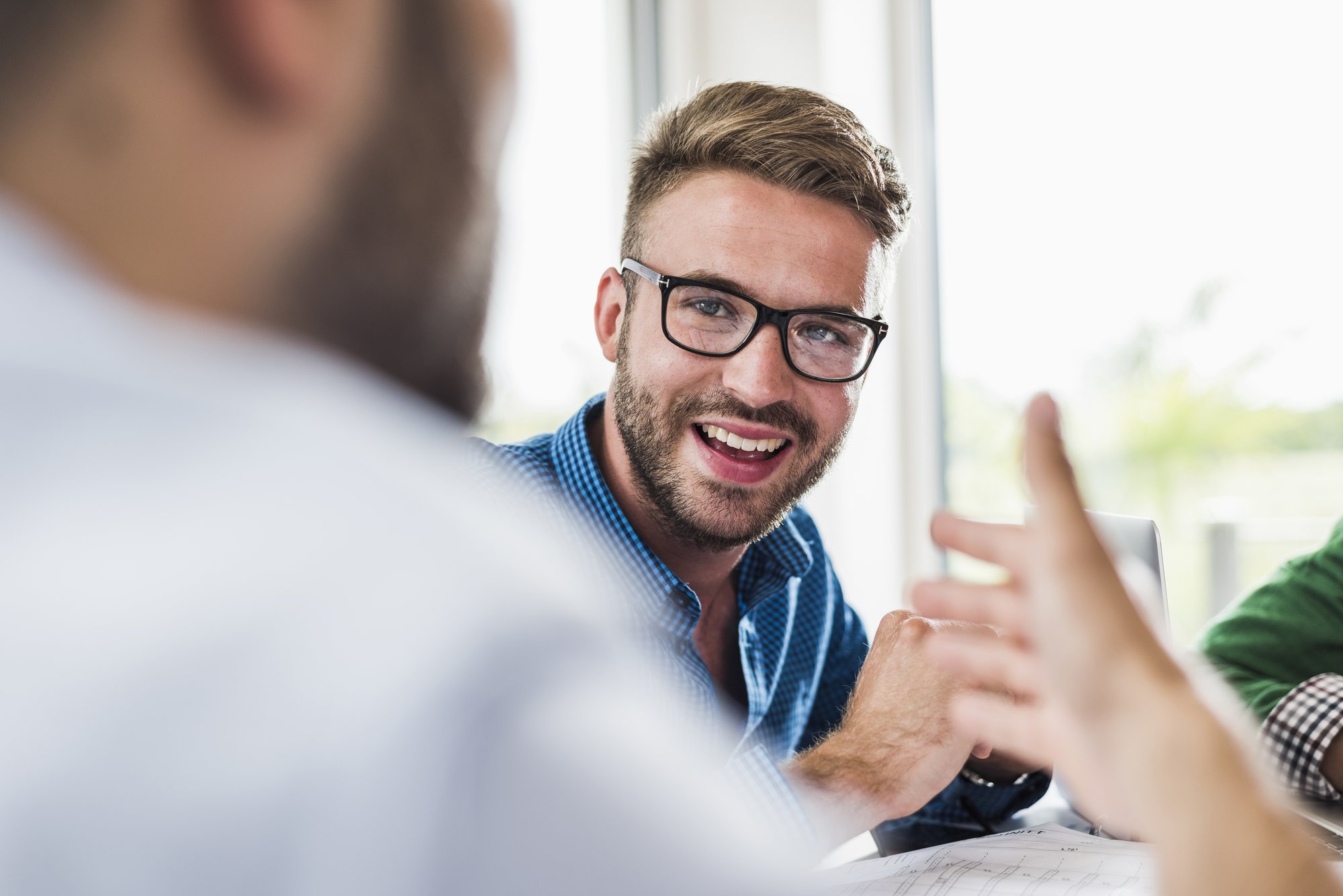 A man with glasses smiling in a meeting.